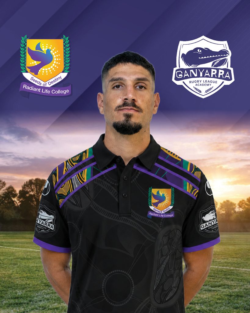 Man in a black rugby polo with purple and green accents standing on a field at sunset college and ganyarra rugby logos appear in the background