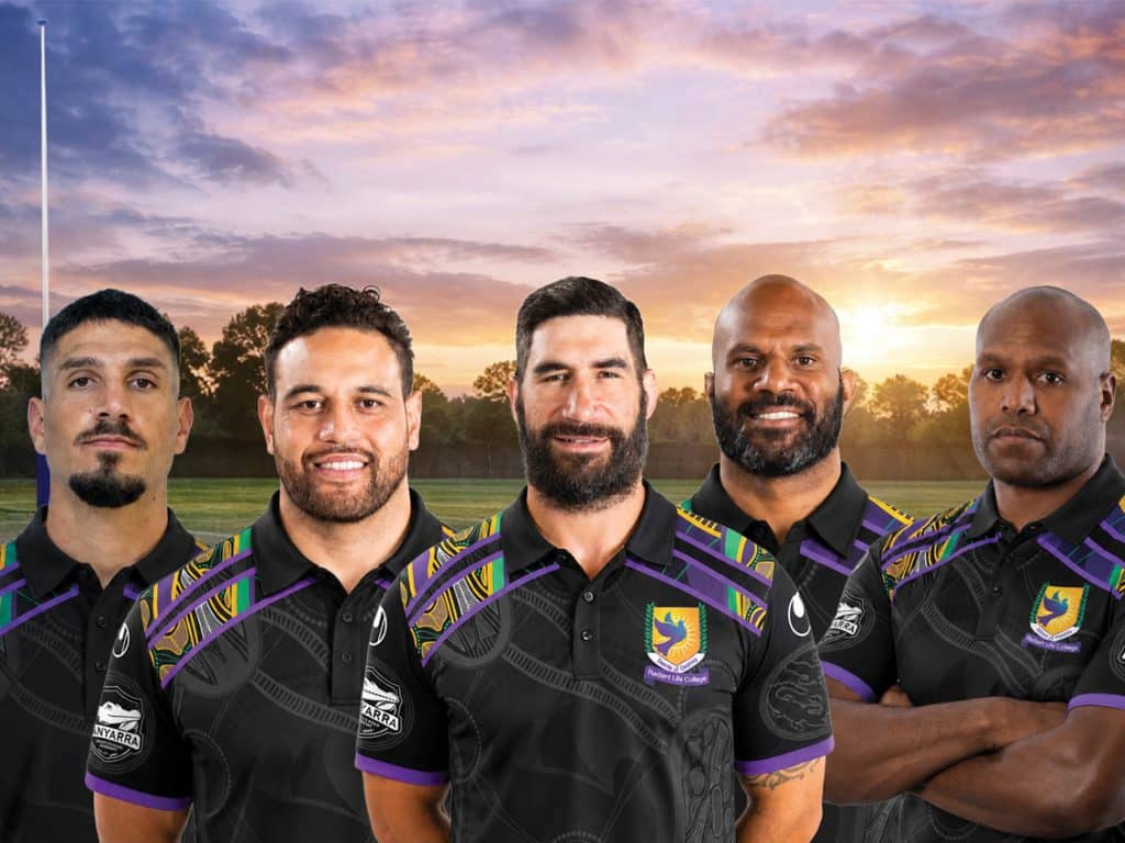 Five rugby players posing on a field at sunset wearing matching black jerseys with purple and yellow trim